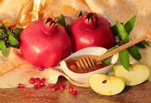 רימונים ותפוחים שיתפזרו על השולחן עם תפאורה נהדרת לארוחת החג